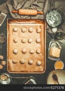 Cookies Dough on baking tray, preparation on kitchen table with tolls and ingredients, top view