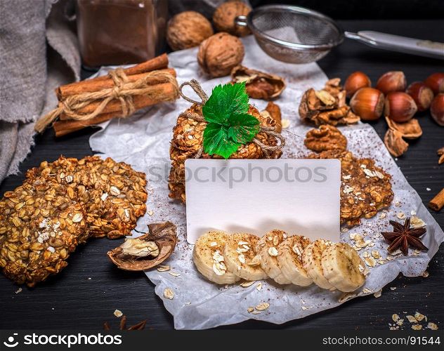 cookies from oat flakes and nuts, in front of an empty white card, black background