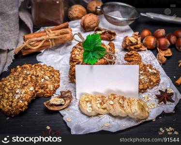 cookies from oat flakes and nuts, in front of an empty white card, black background
