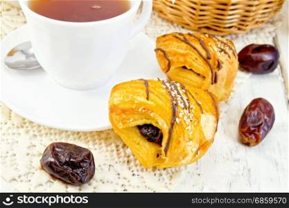 Cookies with dates, tea in a cup on a napkin on the background light wooden boards