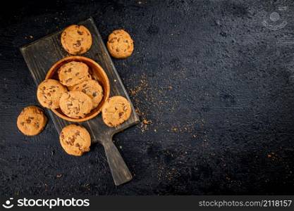Cookies with milk chocolate on a cutting board. On a black background. High quality photo. Cookies with milk chocolate on a cutting board.