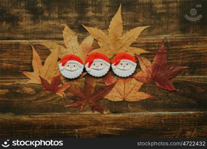 Cookies with Santa Claus shape on fall leaves and a wooden background