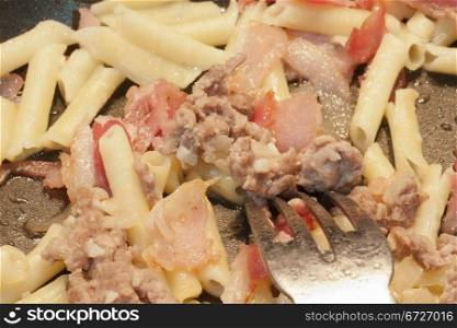 cooking a dish of macaroni with meat and bacon