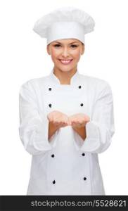 cooking, advertisement and food concept - smiling female chef, cook or baker holding something on palm of hands