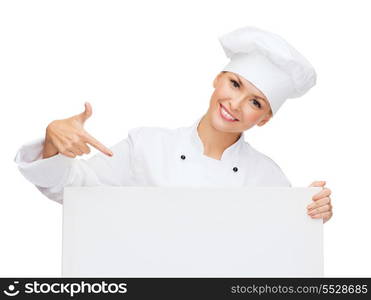 cooking, advertisement and food concept - smiling female chef, cook or baker pointing finger to white blank board