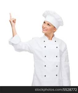 cooking, advertisement and food concept - smiling female chef, cook or baker pointing finger up to something