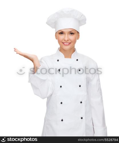cooking, advertisement and food concept - smiling female chef, cook or baker holding something on palm of hand