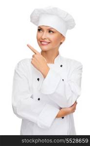 cooking, advertisement and food concept - smiling female chef, cook or baker pointing finger to something