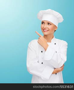 cooking, advertisement and food concept - smiling female chef, cook or baker pointing finger to something