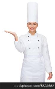 cooking, advertisement and food concept - smiling female chef holding something on palm of hand