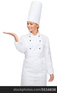 cooking, advertisement and food concept - smiling female chef holding something on palm of hand