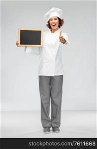cooking, advertisement and people concept - happy smiling female chef holding black chalkboard showing thumbs up over grey background. happy chef with chalkboard showing thumbs up