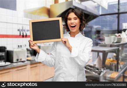 cooking, advertisement and people concept - happy smiling female chef holding black chalkboard over restaurant or kebab shop kitchen background. happy female chef holding chalkboard at kebab shop