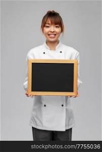 cooking, advertisement and people concept - happy smiling female chef holding black chalkboard over grey background. smiling female chef holding black chalkboard