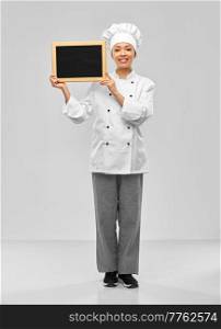 cooking, advertisement and people concept - happy smiling female chef holding black chalkboard over grey background. smiling female chef holding black chalkboard