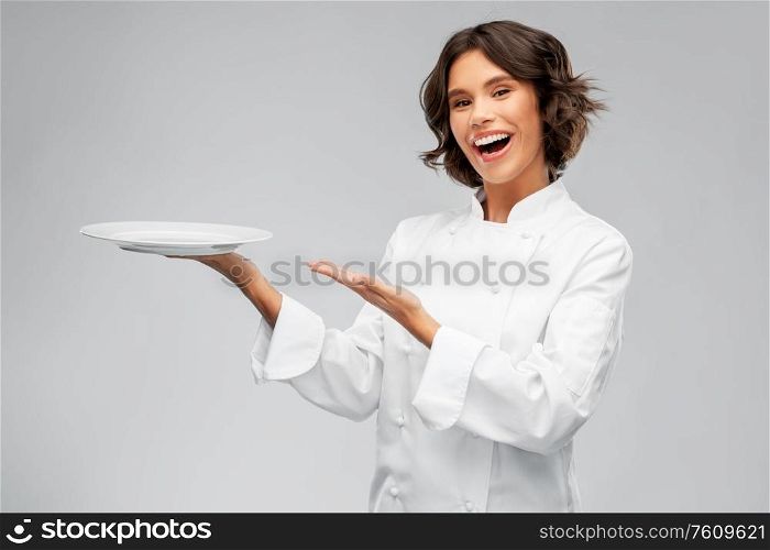 cooking, advertisement and people concept - happy smiling female chef holding empty plate over grey background. smiling female chef holding empty plate