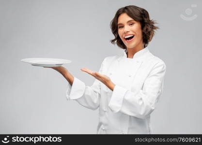 cooking, advertisement and people concept - happy smiling female chef holding empty plate over grey background. smiling female chef holding empty plate