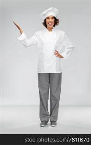 cooking, advertisement and people concept - happy smiling female chef holding something on palm of hand over grey background. smiling female chef holding something on hand
