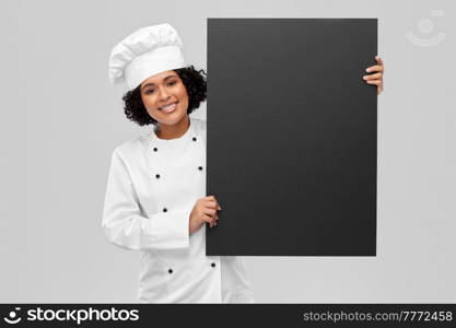 cooking, advertisement and people concept - happy smiling female chef in toque holding black chalkboard over grey background. smiling female chef holding black chalkboard