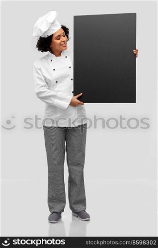 cooking, advertisement and people concept - happy smiling female chef in toque holding black chalkboard over grey background. smiling female chef holding black chalkboard