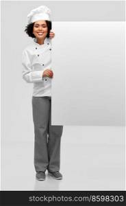 cooking, advertisement and people concept - happy smiling female chef in toque with white board over grey background. smiling female chef with white board
