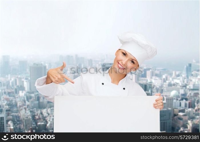 cooking, advertisement and people concept - smiling female chef, cook or baker pointing finger to white blank board over city background