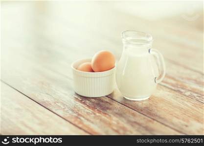cooking and food concept - close up of jugful of milk and eggs in a bowl