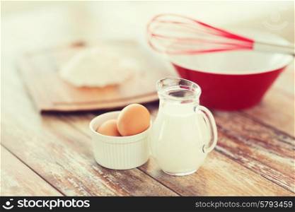 cooking and food concept - close up of jugful of milk, eggs in a bowl and flour