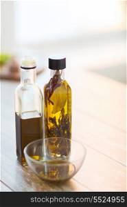 cooking and food concept - close up of two olive oil bottles and bowl of oil