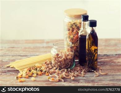 cooking and food concept - close up of two olive oil bottles and pasta in jars