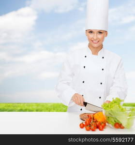 cooking and food concept - smiling female chef chopping vegetables