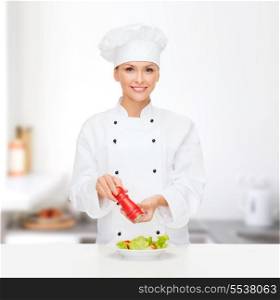 cooking and food concept - smiling female chef, cook or baker preparing salad with salt or pepper mill