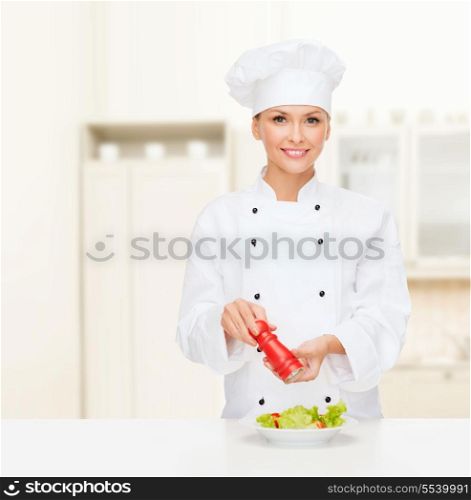 cooking and food concept - smiling female chef, cook or baker preparing salad with salt or pepper mill
