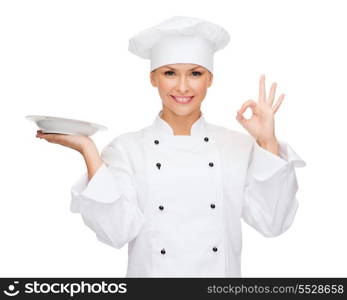 cooking and food concept - smiling female chef, cook or baker with empty plate showing ok sign