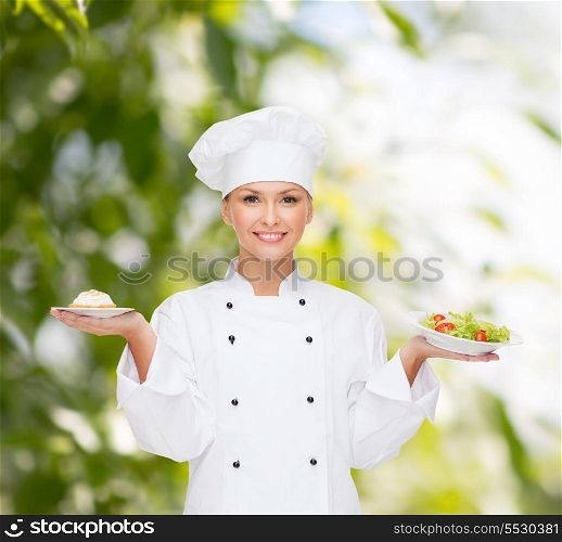 cooking and food concept - smiling female chef, cook or baker with salad and cake on plates