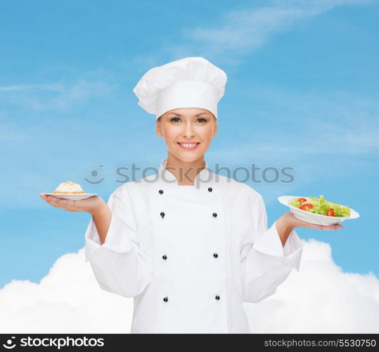 cooking and food concept - smiling female chef, cook or baker with salad and cake on plates