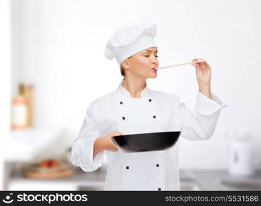 cooking and food concept - smiling female chef, cook or baker with pan and spoon tasting food