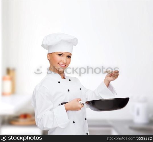 cooking and food concept - smiling female chef, cook or baker with pan and spoon tasting food