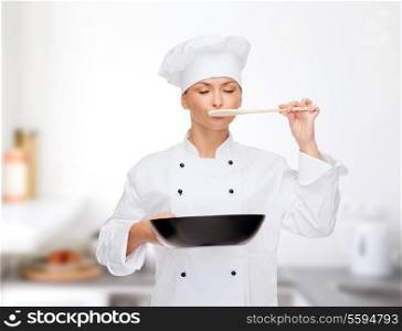 cooking and food concept - smiling female chef, cook or baker with pan and spoon tasting food