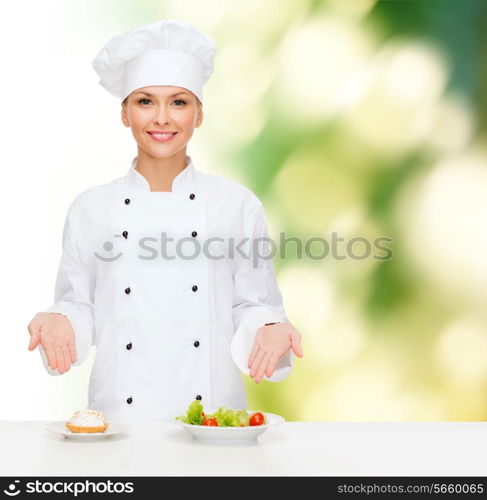 cooking and food concept - smiling female chef, cook or baker with salad and cake on plates