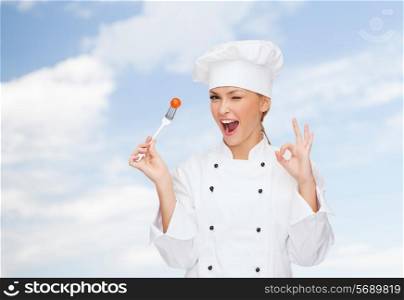 cooking and food concept - smiling female chef, cook or baker with fork and tomato showing ok sign