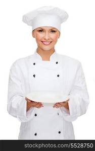 cooking and food concept - smiling female chef, cook or baker with empty plate