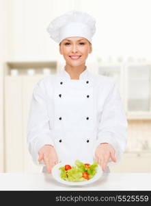 cooking and food concept - smiling female chef, cook or baker with salad on plate