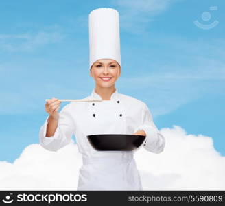 cooking and food concept - smiling female chef with pan and spoon tasting food