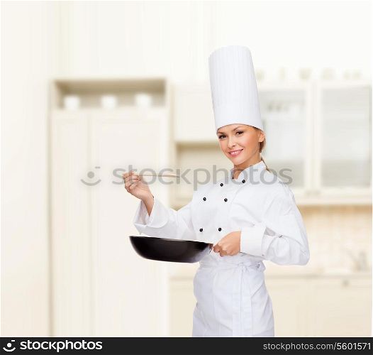 cooking and food concept - smiling female chef with pan and spoon tasting food