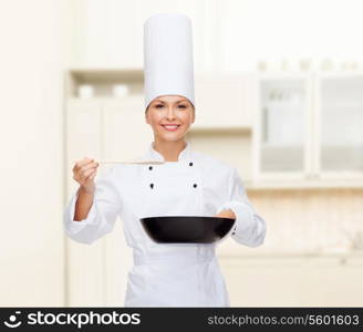 cooking and food concept - smiling female chef with pan and spoon tasting food