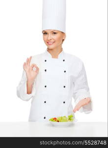 cooking and food concept - smiling female chef with salad on plate and ok sign