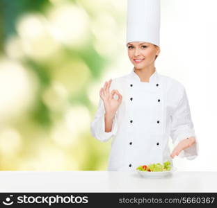 cooking and food concept - smiling female chef with salad on plate and ok sign