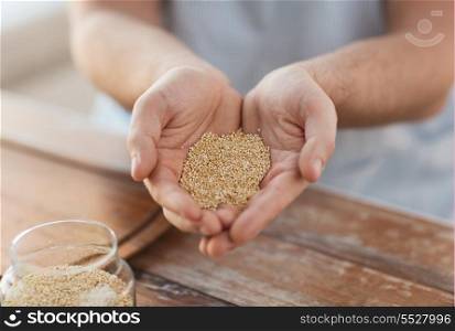 cooking and home concept - cloes up of male cupped hands with quinoa