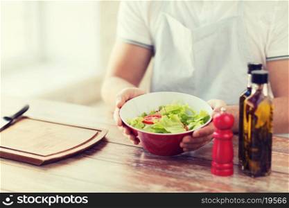 cooking and home concept - close of male hand holding a bowl with salad
